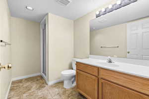 Full bath featuring vanity, a shower stall, recessed lighting, a textured ceiling, and light tile patterned flooring