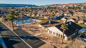 Aerial view of clubhouse area featuring a pond and guest parking.