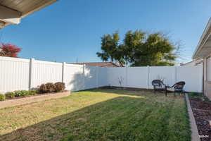 View of fenced backyard with lawn and space to gather with friends.