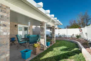Fenced backyard featuring a patio area, outdoor dining space, flower beds and lawn.