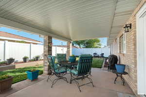 Fenced backyard featuring a patio area, outdoor dining space, flower beds and grill space.