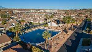 Aerial view of property's clubhouse location featuring a pond and nearby suburban area
