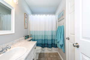 Full bath featuring tile flooring, vanity, curtained shower and linen closet.