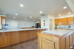 Kitchen with light countertops, a center island, recessed lighting, and a peninsula perfect for gatherings and cooking classes!