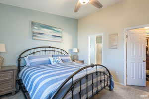 Primary bedroom with a ceiling fan and ensuite bath