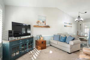 Carpeted open living area with lofted ceiling.