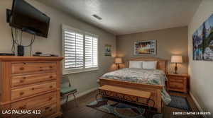 Bedroom with a textured ceiling and dark wood-style floors
