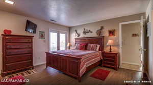 Bedroom with a textured ceiling, dark wood-style floors, and access to outside