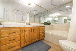 Bathroom featuring light tile patterned floors, a garden tub, vanity, and tiled shower