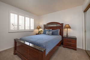 Bedroom with light colored carpet and a closet