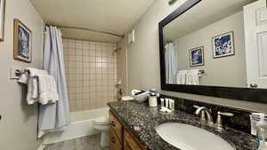 Full bathroom featuring vanity, shower / bath combo, a textured ceiling, light wood-type flooring, and a textured wall