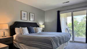 Carpeted bedroom featuring access to exterior and a textured ceiling