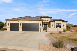 Prairie-style home with stone siding, a garage, stucco siding, and concrete driveway