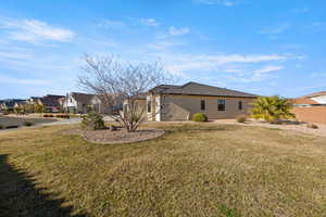 View of side of property featuring a yard, stucco siding, and a residential view
