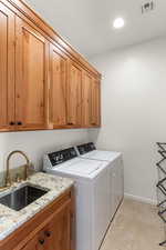 Laundry area with washer and dryer, cabinet space, and recessed lighting