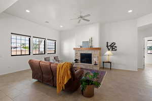 Living room with a fireplace, ceiling fan, recessed lighting, and light tile patterned floors