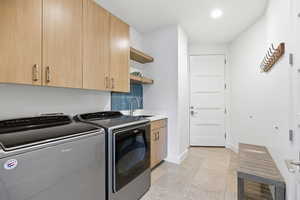 Laundry area with light tile patterned flooring, cabinet space, independent washer and dryer, and recessed lighting