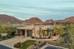 View of front of property with a mountain view, stucco siding, concrete driveway, and an attached garage