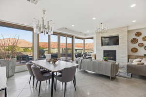 Dining room with a chandelier, a mountain view, a premium fireplace, light tile patterned floors, and recessed lighting