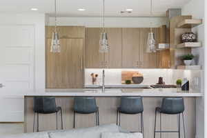 Kitchen with modern cabinets, open shelves, a kitchen breakfast bar, light stone countertops, and recessed lighting