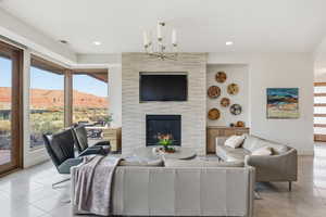 Living room featuring a tiled fireplace, light tile patterned floors, and a chandelier