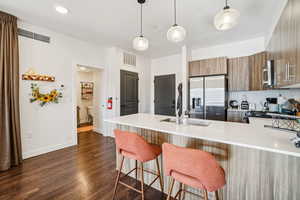 Kitchen with modern cabinets, a peninsula, light stone counters, decorative light fixtures, and tasteful backsplash