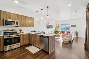 Kitchen featuring brown cabinetry, stainless steel appliances, a peninsula, modern cabinets, and recessed lighting