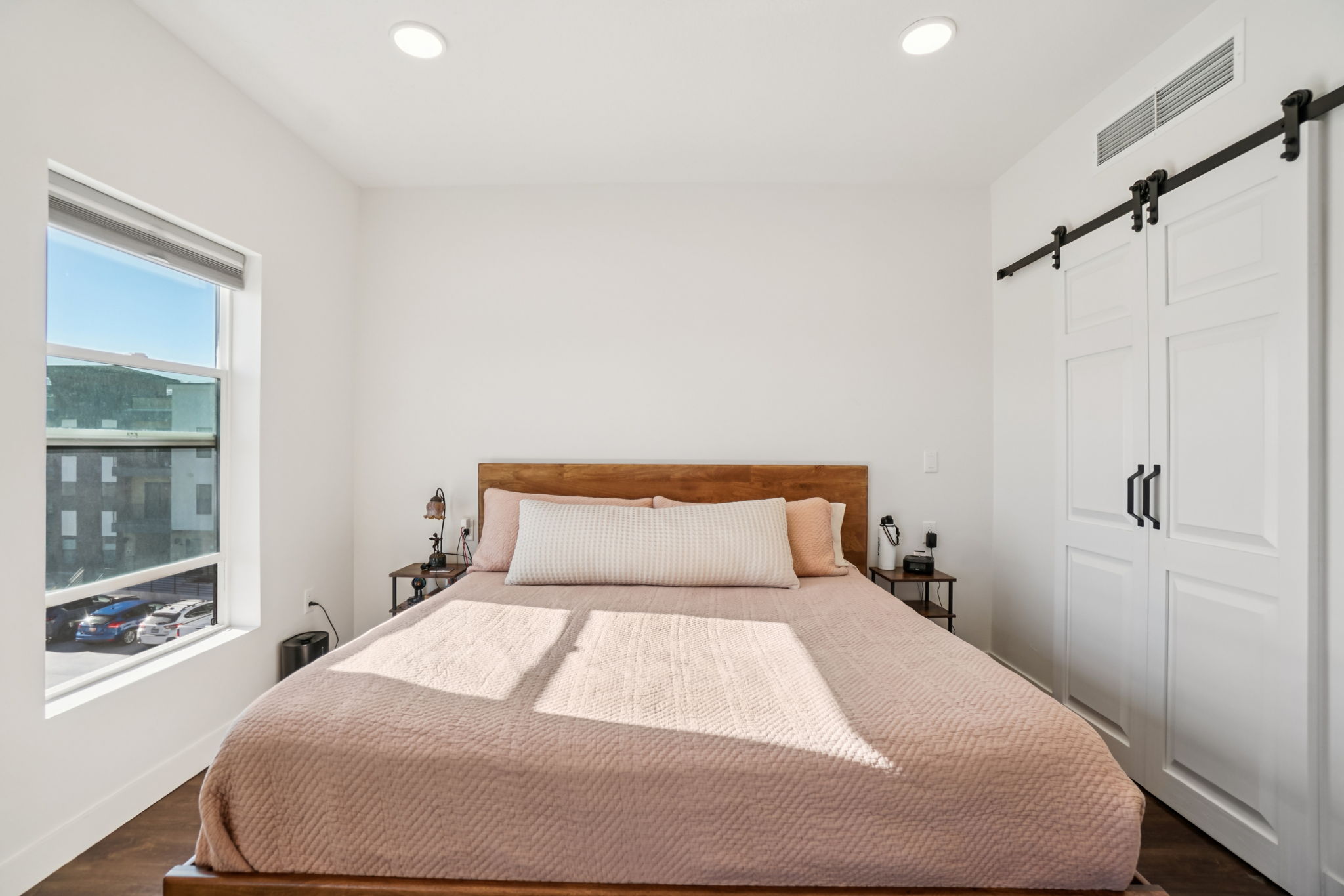 Bedroom with a barn door, a closet, dark wood-style flooring, and recessed lighting