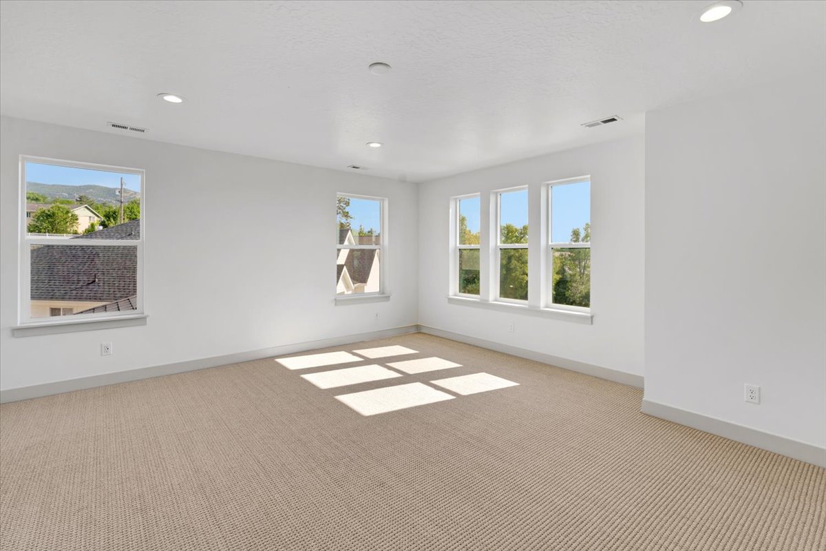 Spacious room featuring multiple windows, recessed ceiling lighting, light-toned carpeting, and white walls