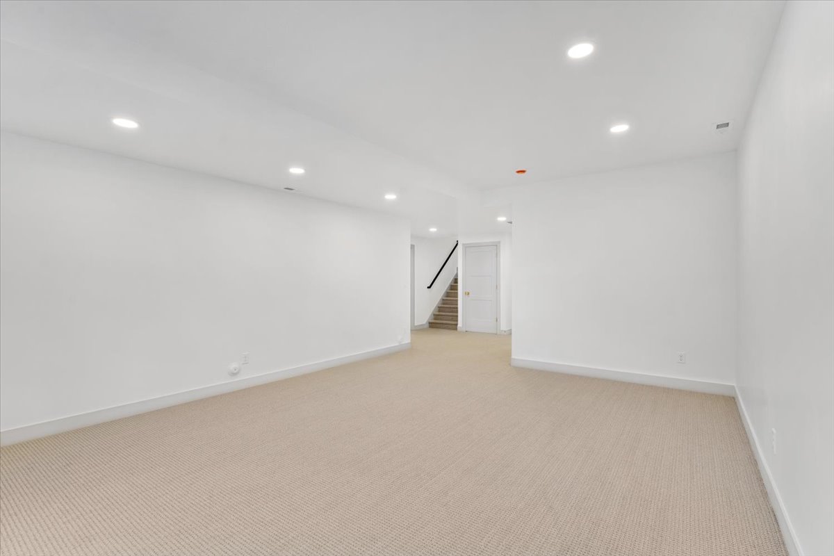 Spacious room with recessed lighting, light-toned carpeting, white walls, and white baseboards