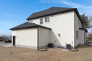Rear view of property featuring stucco siding, roof with shingles, and an attached garage