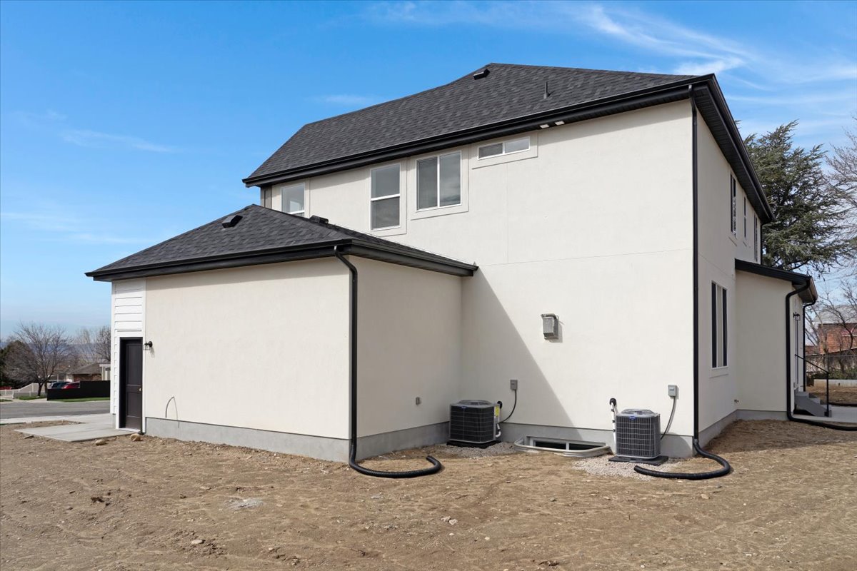 Newly constructed residence featuring a white stucco exterior and dark shingle roofing
