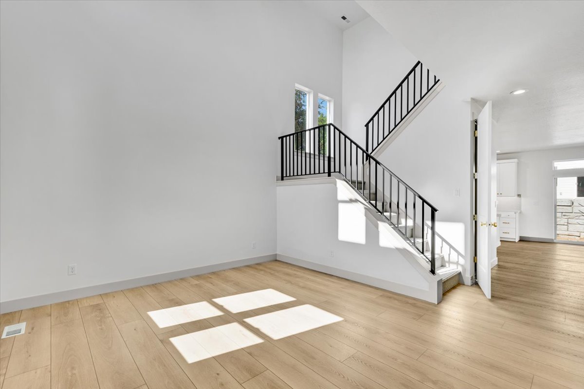 Contemporary interior featuring a prominent staircase with black metal railings, light wood-finish flooring, and crisp white walls