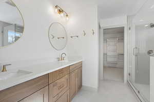 Full bath with a walk in closet, double vanity, and a shower stall