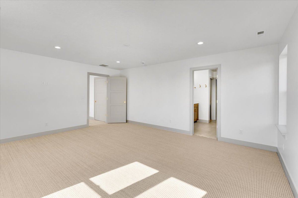Spacious room featuring neutral carpeting, white walls, recessed lighting, and multiple doorways
