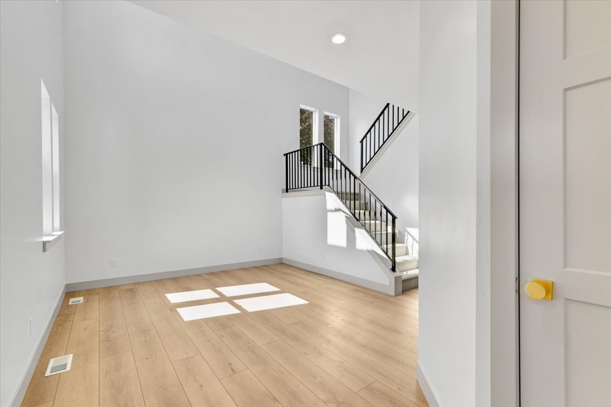 Open-concept living space featuring wood-finish flooring, high ceilings, and recessed lighting