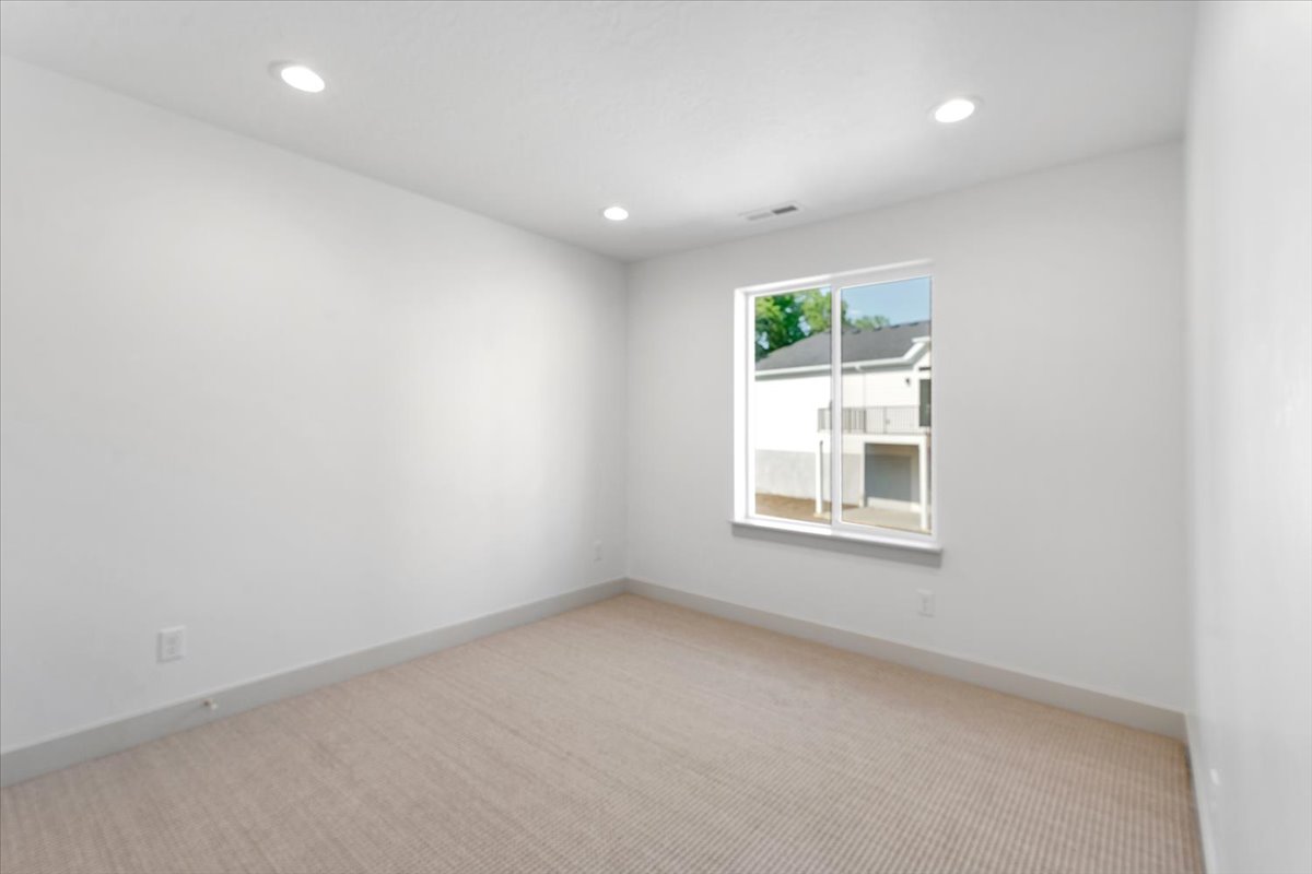 Neutral wall palette, recessed lighting, double-pane window, and textured carpet flooring