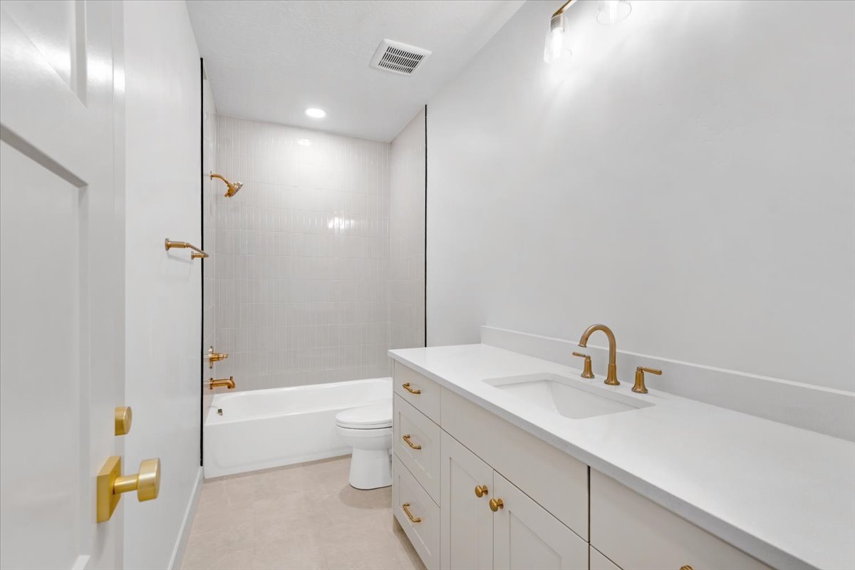 Bathroom featuring a white vanity with gold-tone hardware, white countertop, and integrated sink