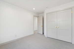 Unfurnished bedroom with light colored carpet, recessed lighting, and a closet