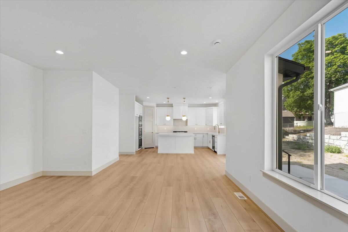 Open-concept living space featuring wood-finish flooring, recessed lighting, and a kitchen with white cabinetry, a center island, and pendant lighting