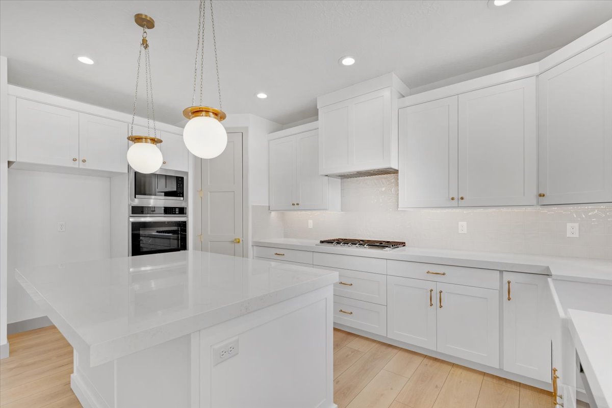 Kitchen featuring light wood-finish flooring and white cabinetry with brass hardware