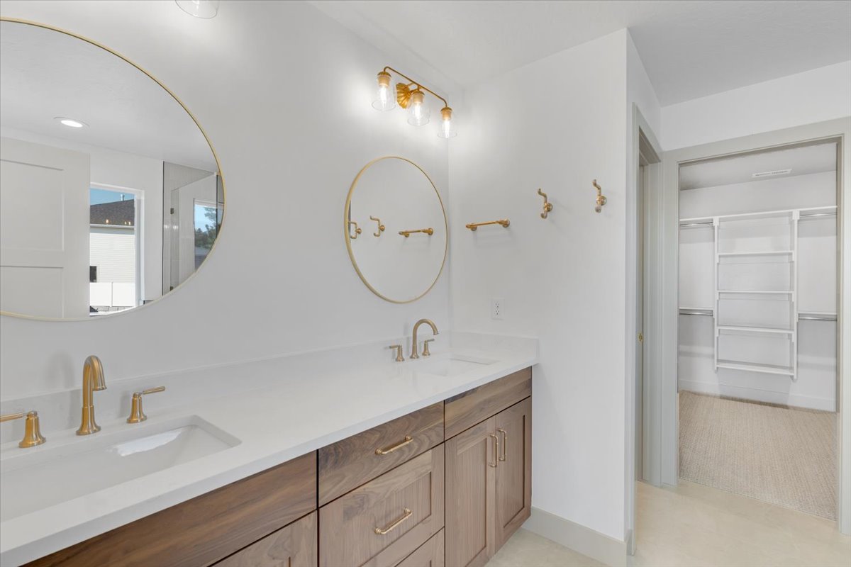 Double vanity featuring white countertops, wood-finish cabinetry, and gold-tone fixtures
