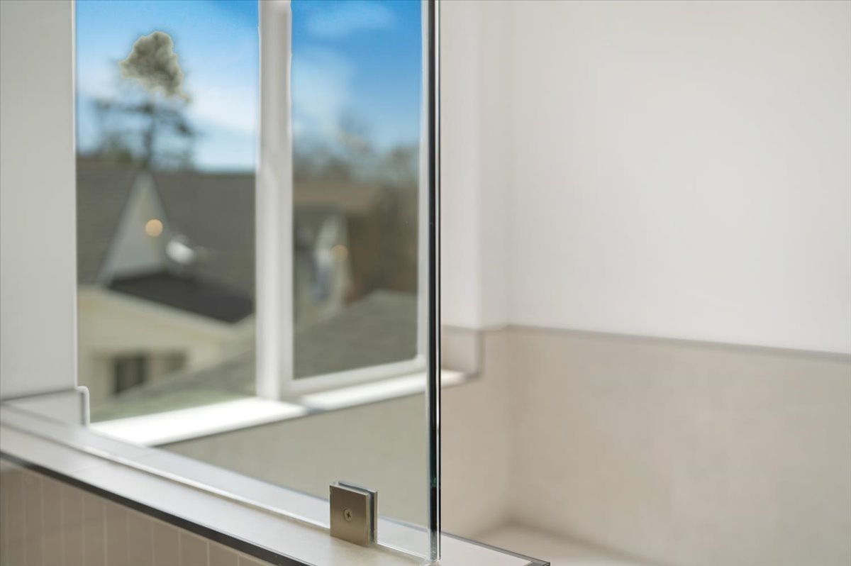 Frameless glass shower enclosure with brushed nickel hardware, set against a tiled half-wall