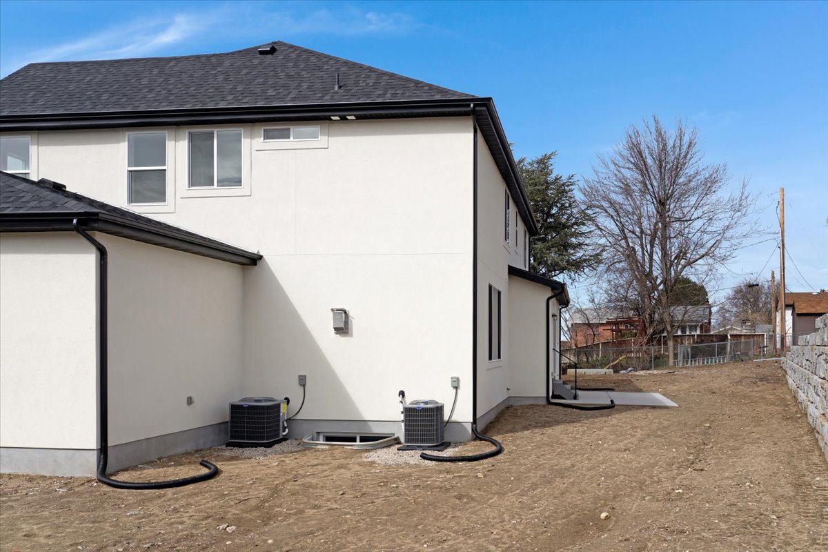 Modern stucco exterior featuring a dark asphalt shingle roof and black gutters