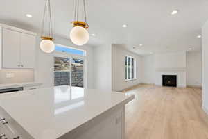 Kitchen featuring white cabinets, light wood finished floors, plenty of natural light, and light stone countertops