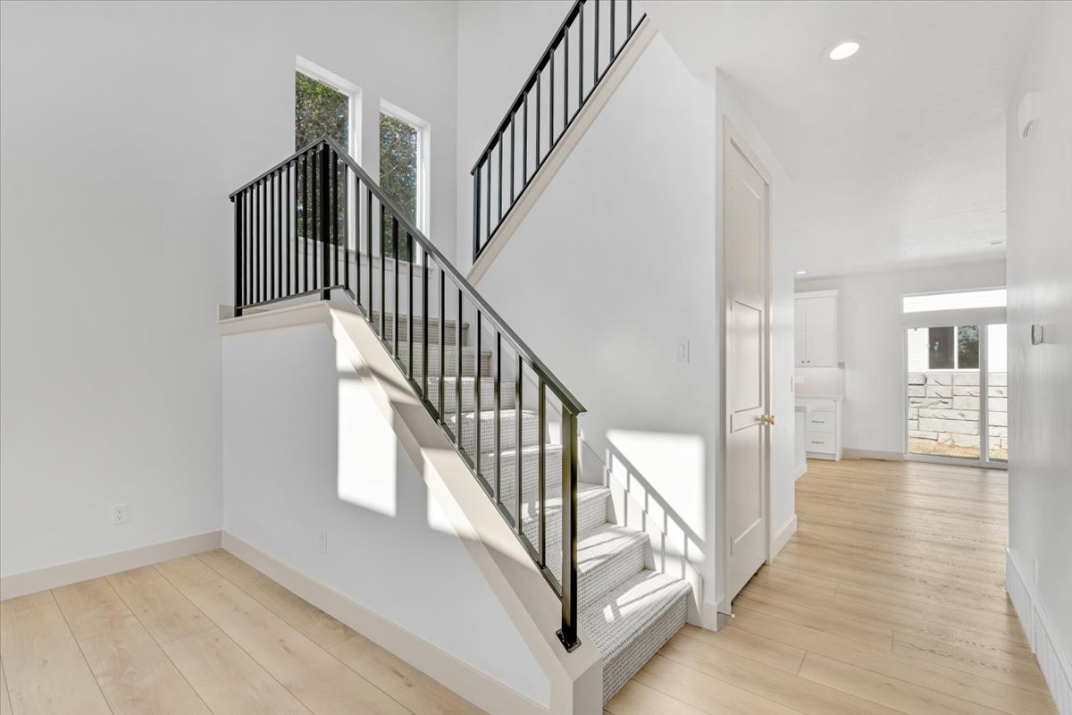 Interior staircase with black metal balusters and carpeted treads, complemented by light wood-finish flooring