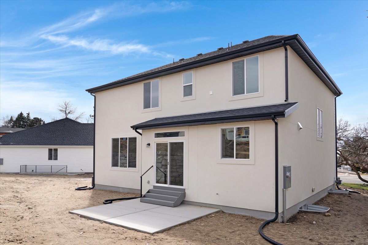 Contemporary two-story exterior with stucco siding, black asphalt shingle roof, and white-framed windows