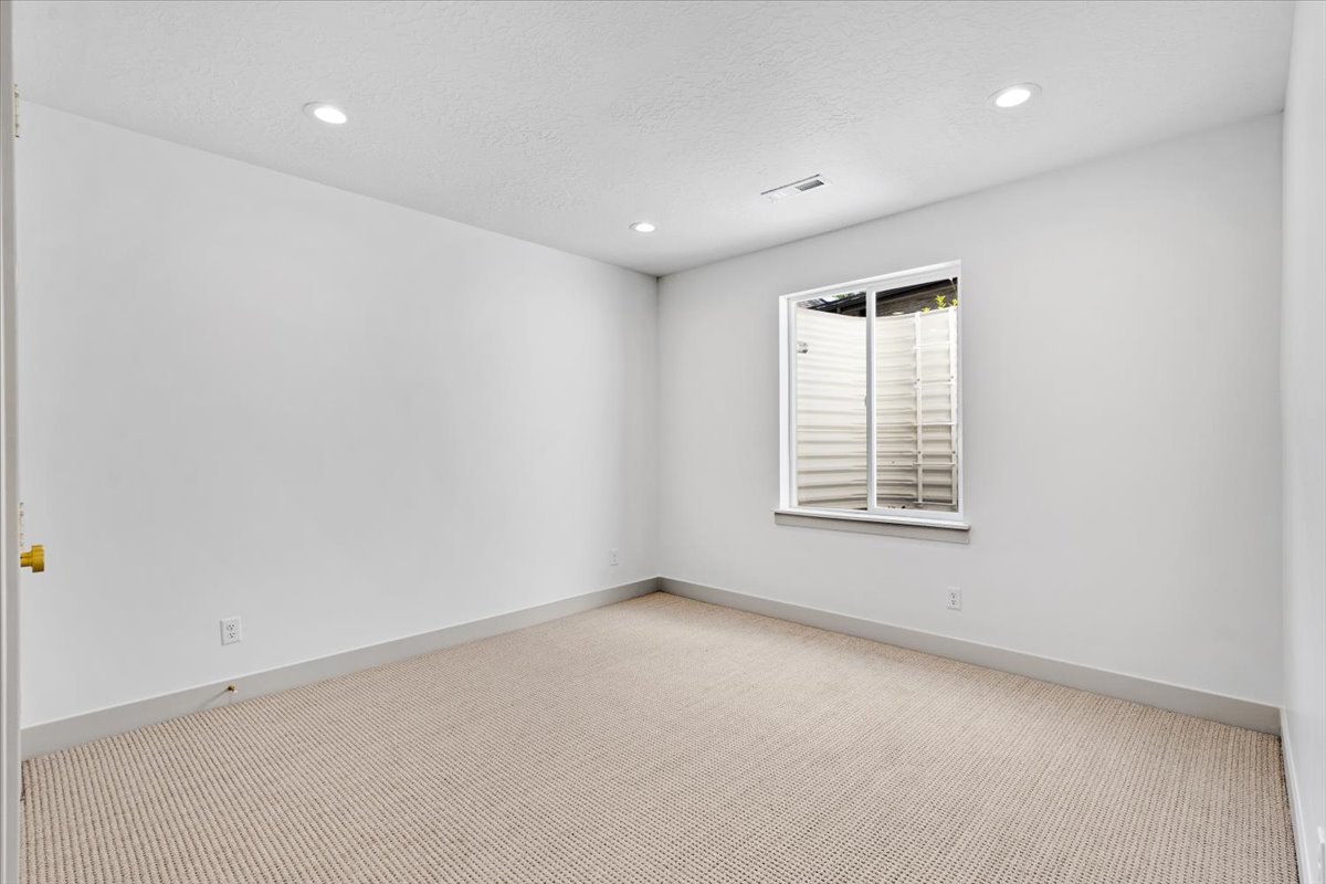 Room featuring recessed lighting, a neutral carpet, white walls, and a window with a window well