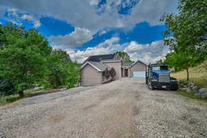 View of front facade featuring gravel driveway, roof mounted solar panels, and a garage