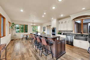 Kitchen featuring backsplash, a barn door, a breakfast bar, a kitchen island, and recessed lighting